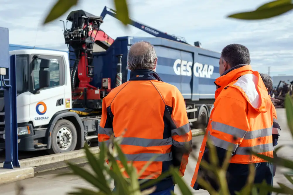 Zwei Gescrap-Mitarbeiter mit einem Lastwagen im Hintergrund